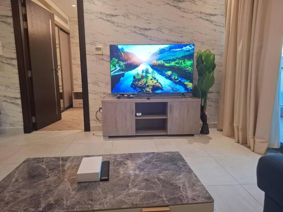 a flat screen tv sitting on a stand in a living room at Home on Holiday -Apartments in Manama