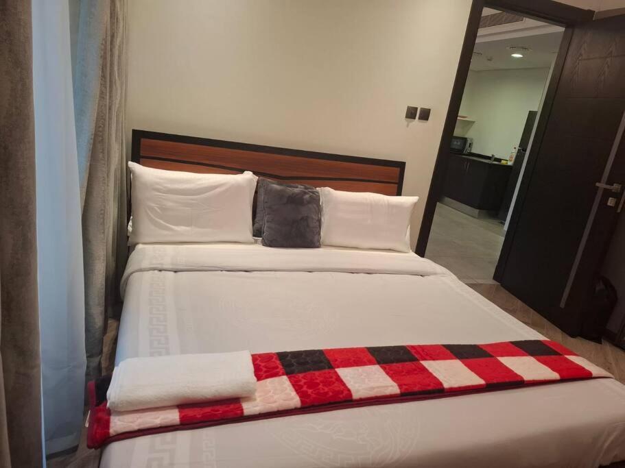 a bed with a red and black plaid blanket on it at Home on Holiday -Apartments in Manama