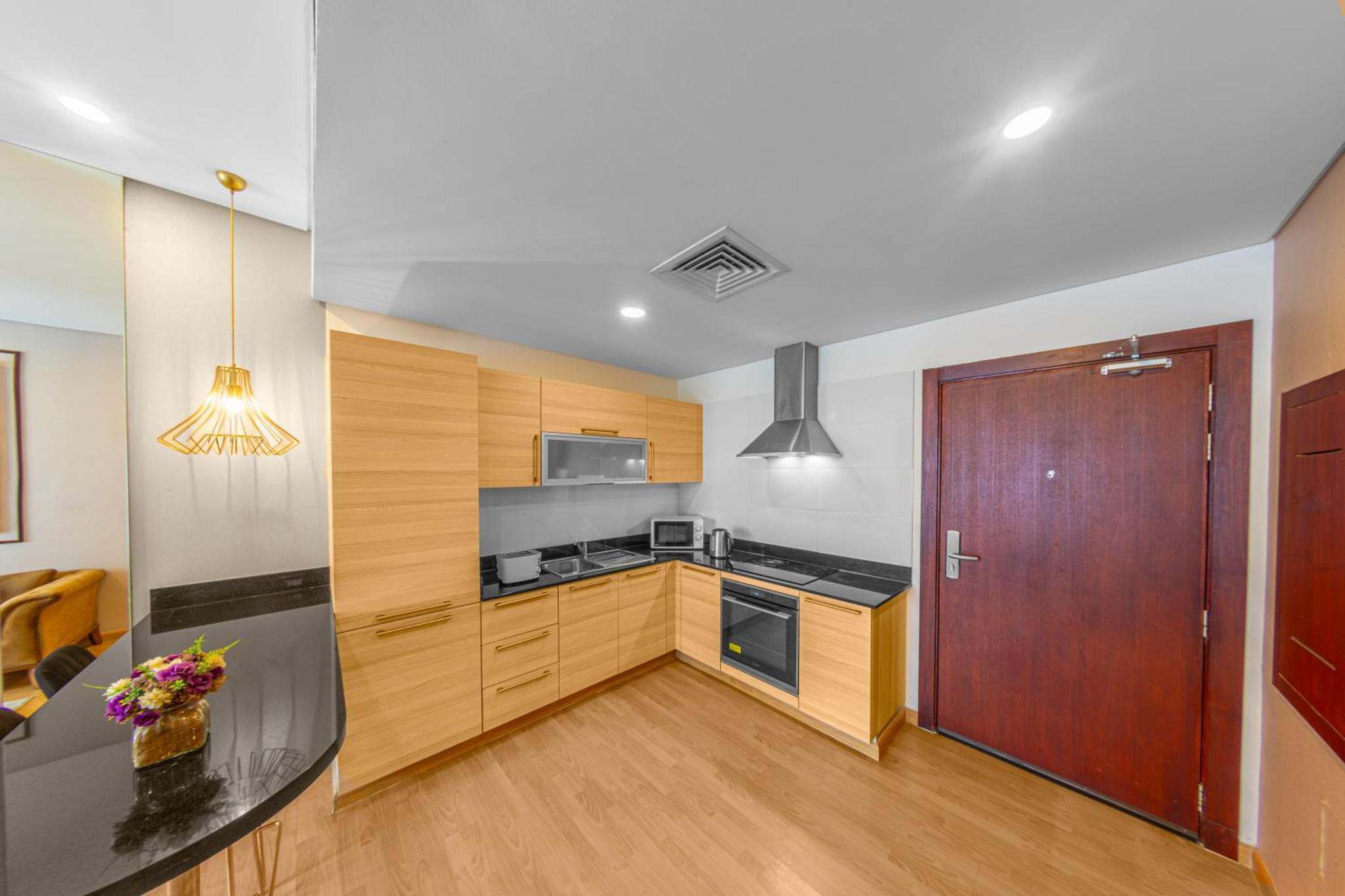 a kitchen with wooden cabinets and a wooden door at Afaq Tower in Manama