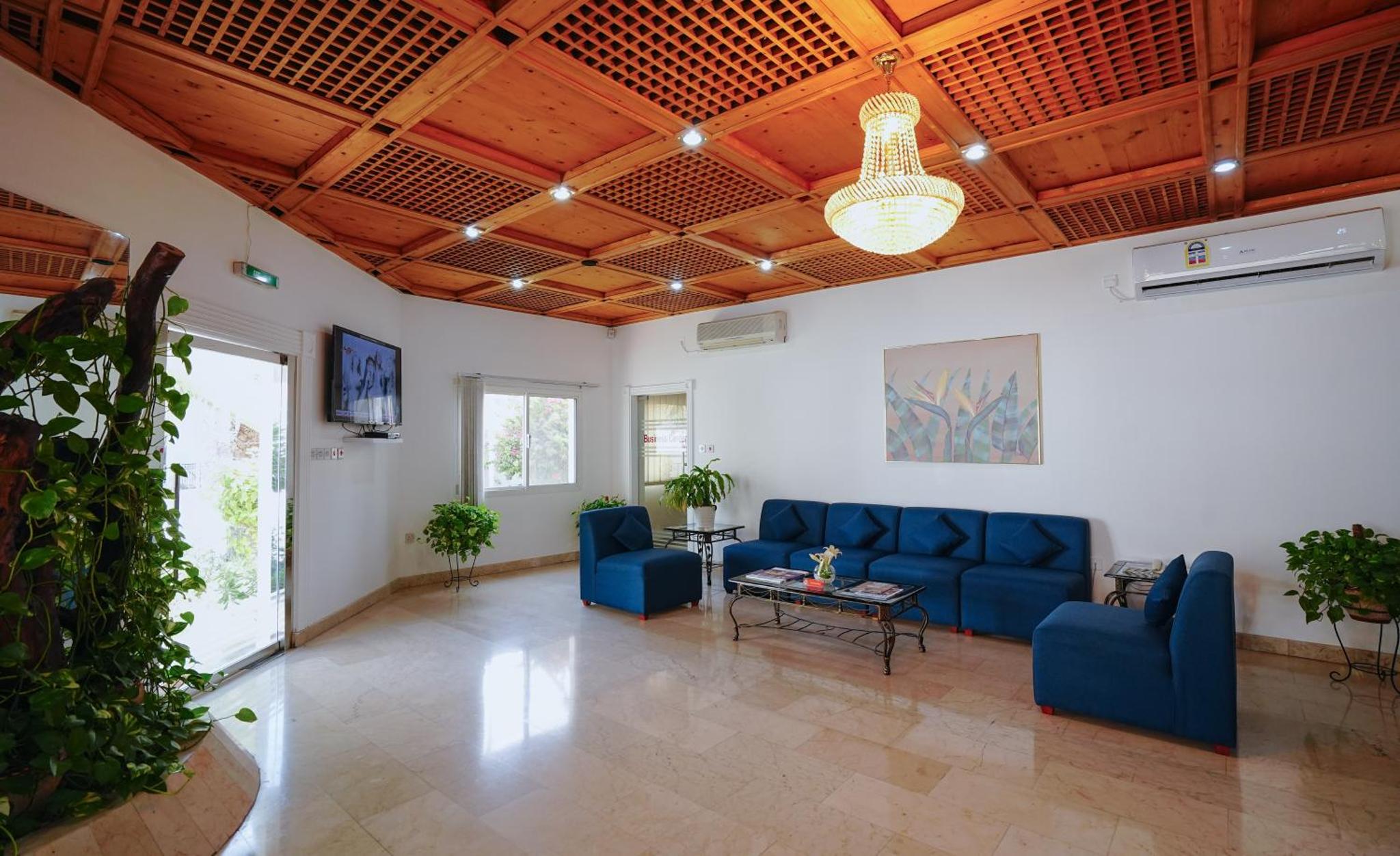 a living room with blue furniture and a wooden ceiling at Tropicana Hotel in Manama