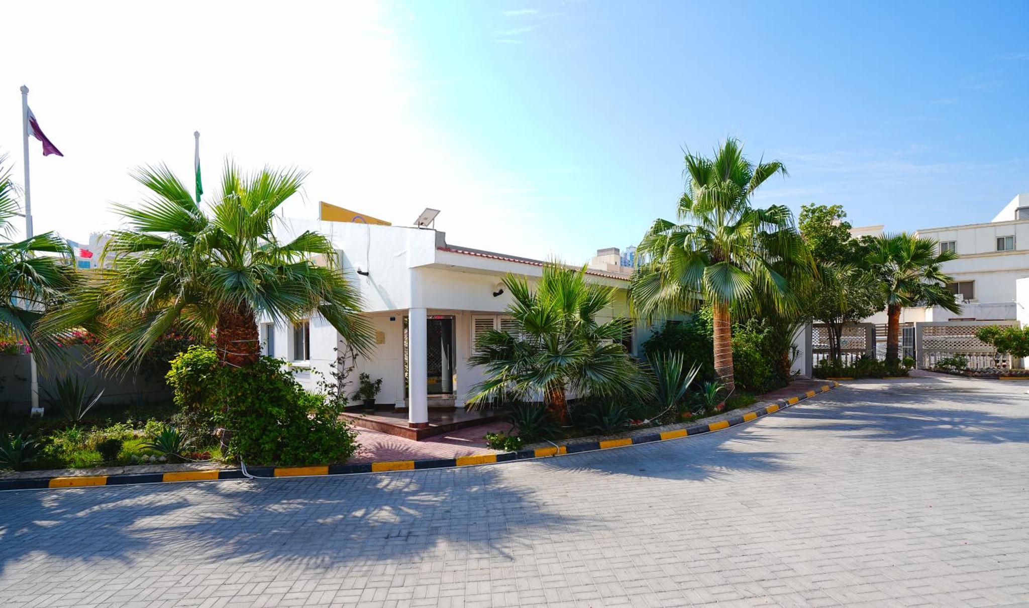 a building with palm trees in front of it at Tropicana Hotel in Manama