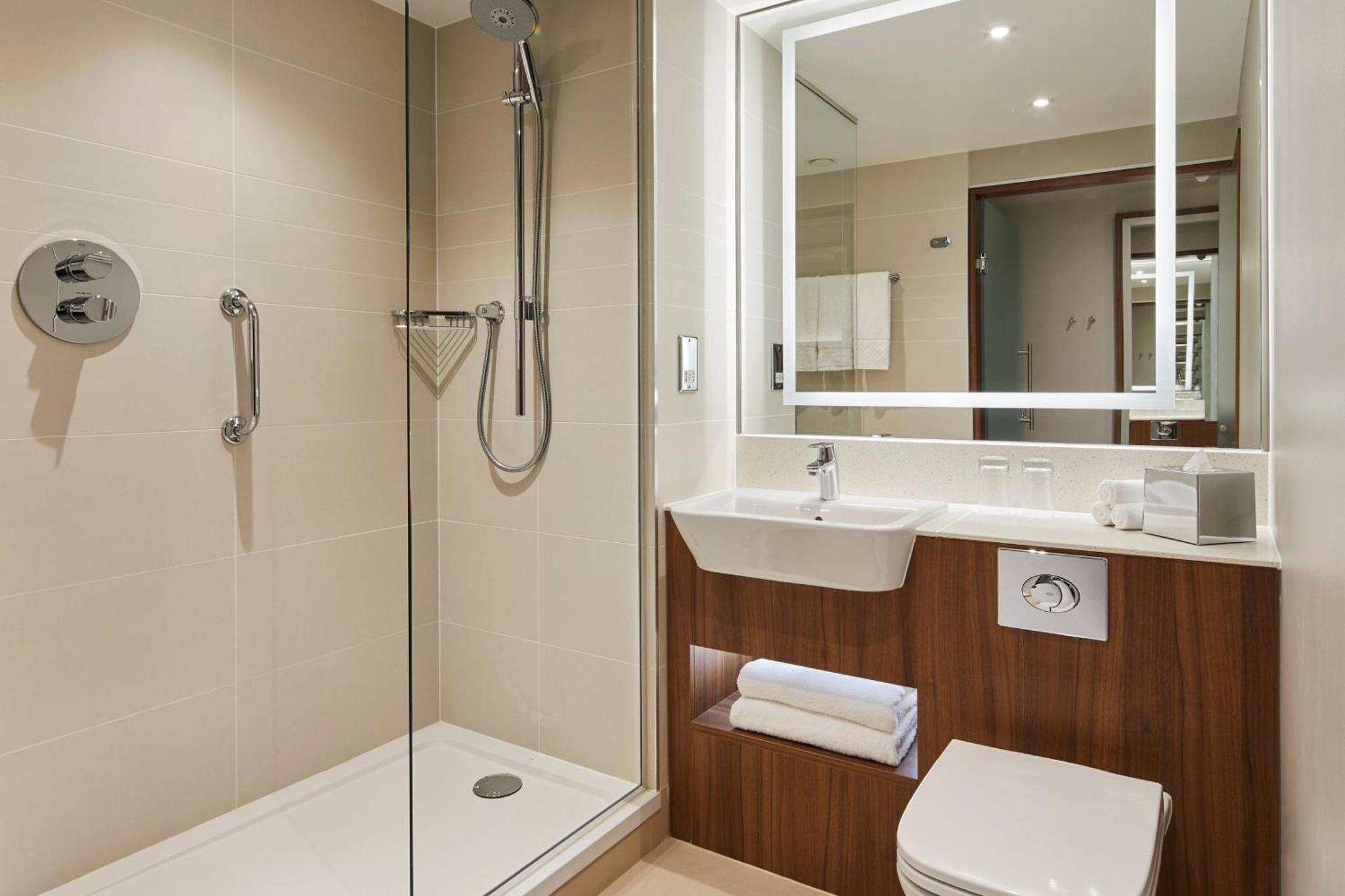 a bathroom with a shower and a sink and a toilet at Courtyard by Marriott London City Airport in London