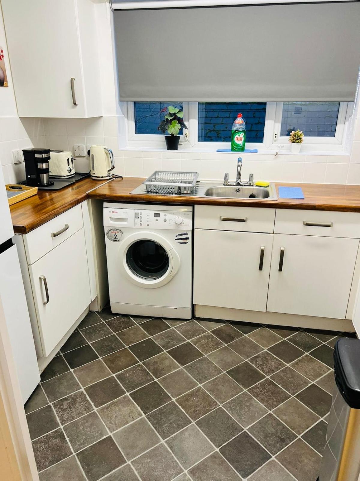 a kitchen with a washing machine and a sink at Thematic London Apartment in Holloway in London