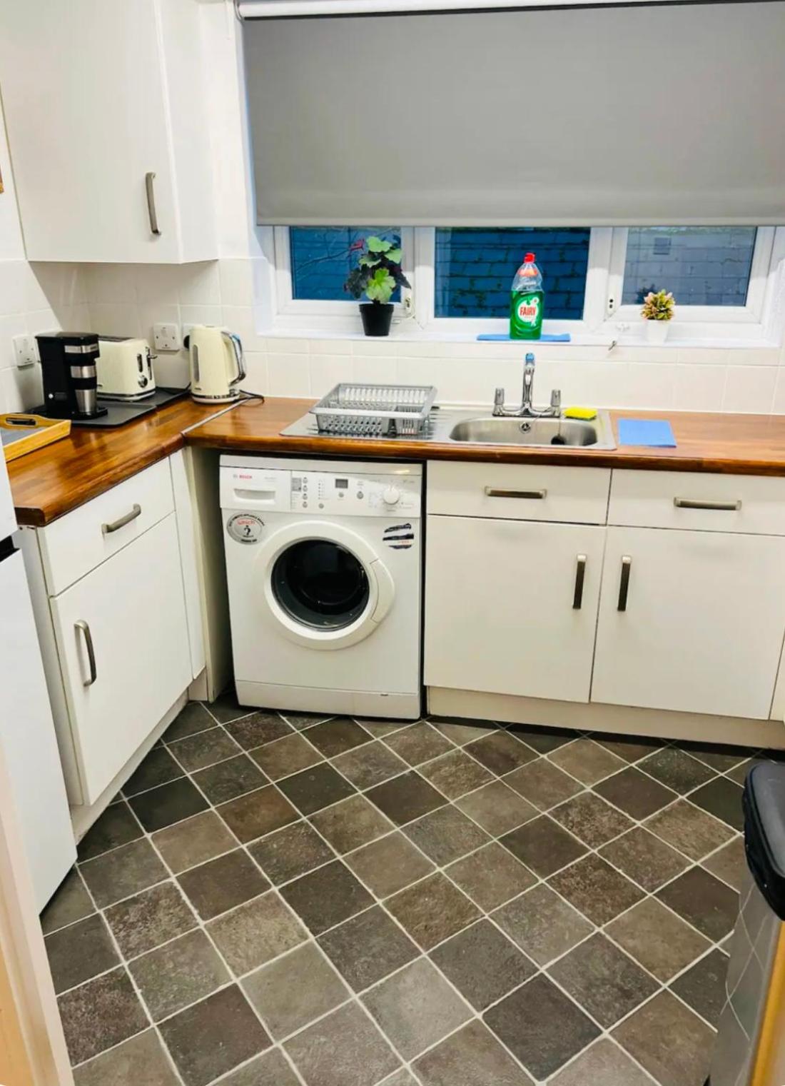 a kitchen with a washing machine and a sink at Thematic London Apartment in Holloway in London