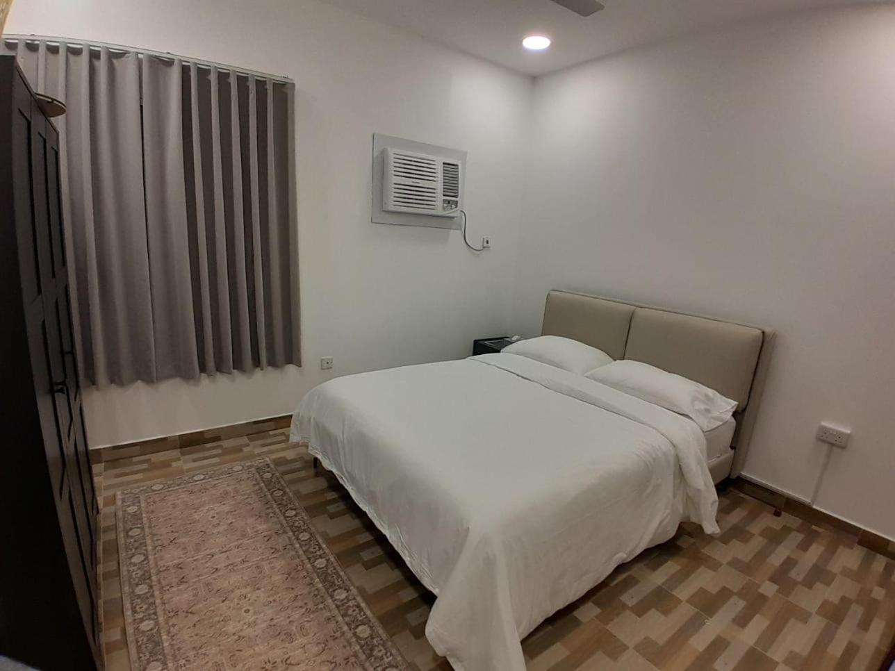 a bedroom with a large white bed and a window at AlWadi AGROSERNE - 2BR West Riffa Apartment in Ar Rifā‘
