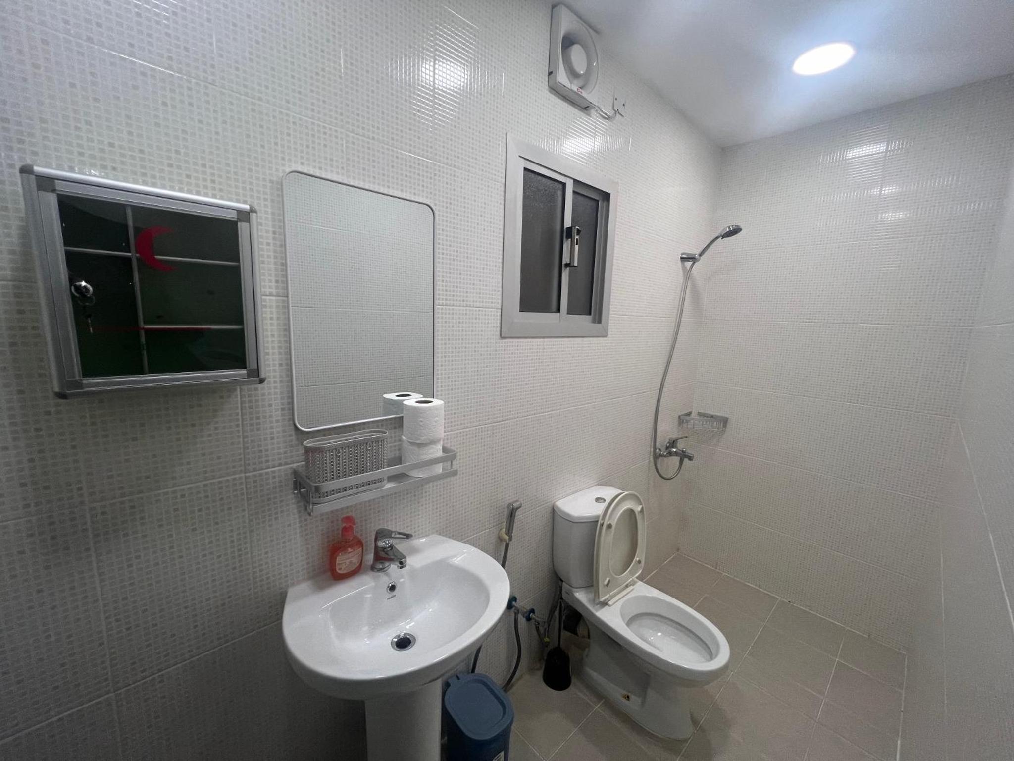 a bathroom with a toilet and a sink and a mirror at AlWadi AGROSERNE - 2BR West Riffa Apartment in Ar Rifā‘