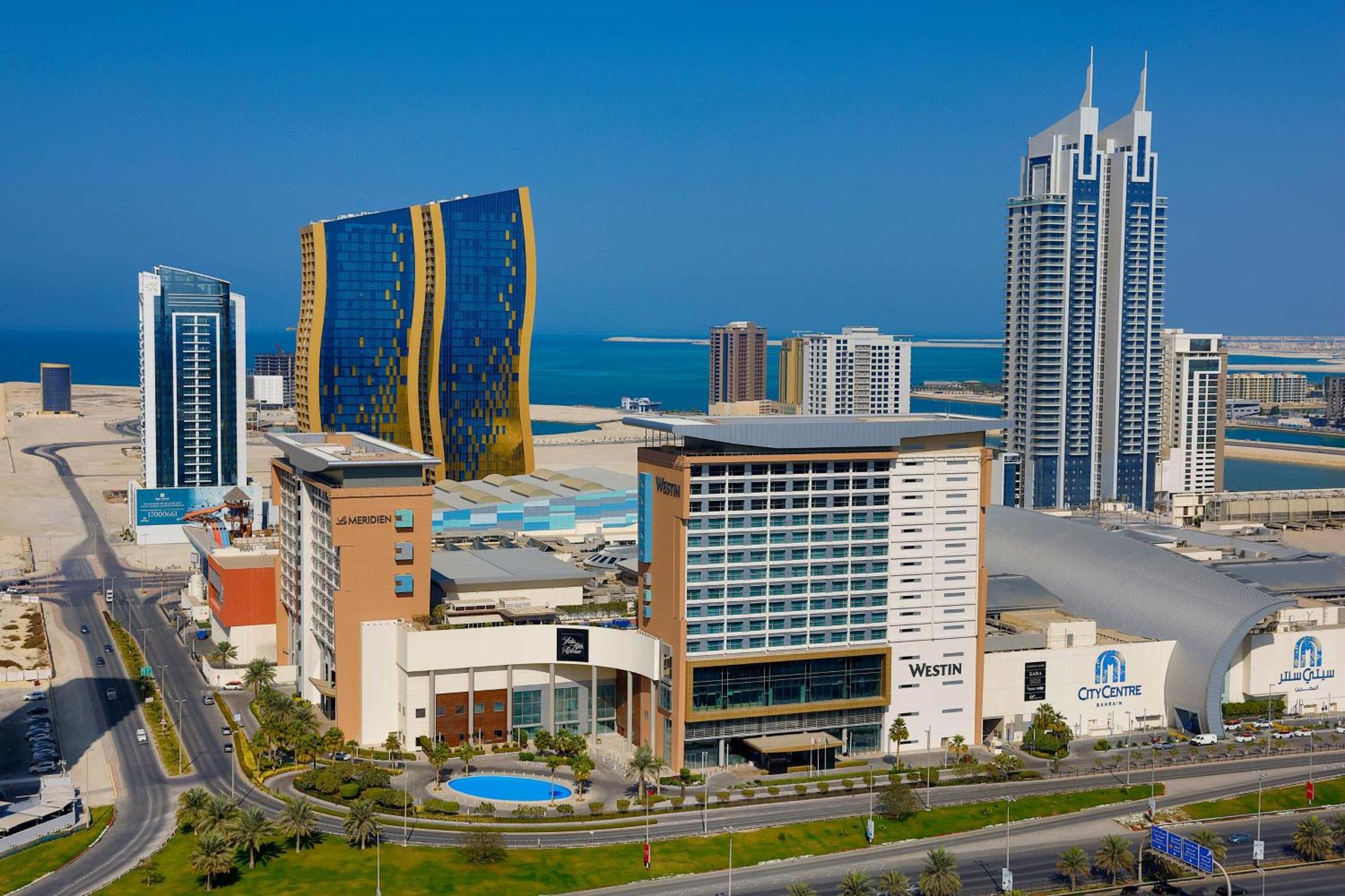 a city skyline with tall buildings and the ocean at Le Meridien City Centre Bahrain in Manama