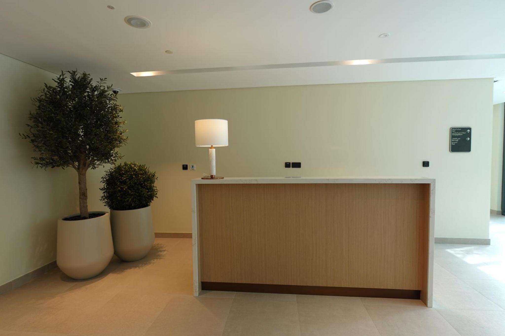 a lobby with two potted trees and a desk at Address Vista Bahrain in Rayyā +68 photos