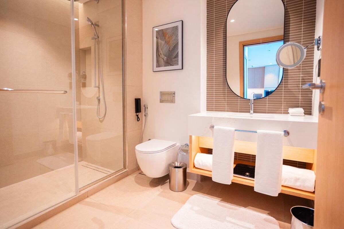a bathroom with a shower and a toilet and a mirror at Spacious 2BDR Address Vista PrivateTerrace in Amwaj Island