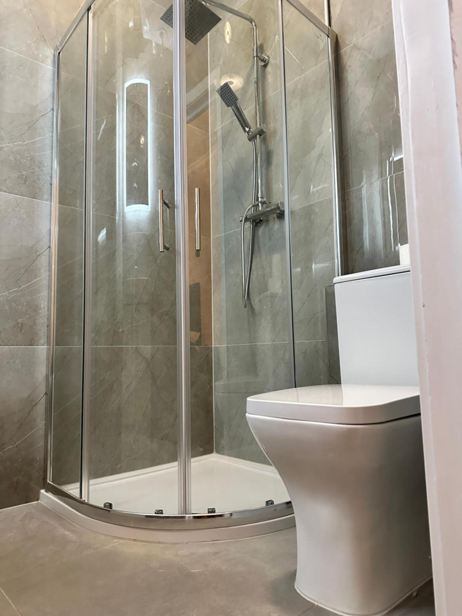 a bathroom with a glass shower with a toilet at Green Ariana Hotel - near Wembley and central London in London +40 photos