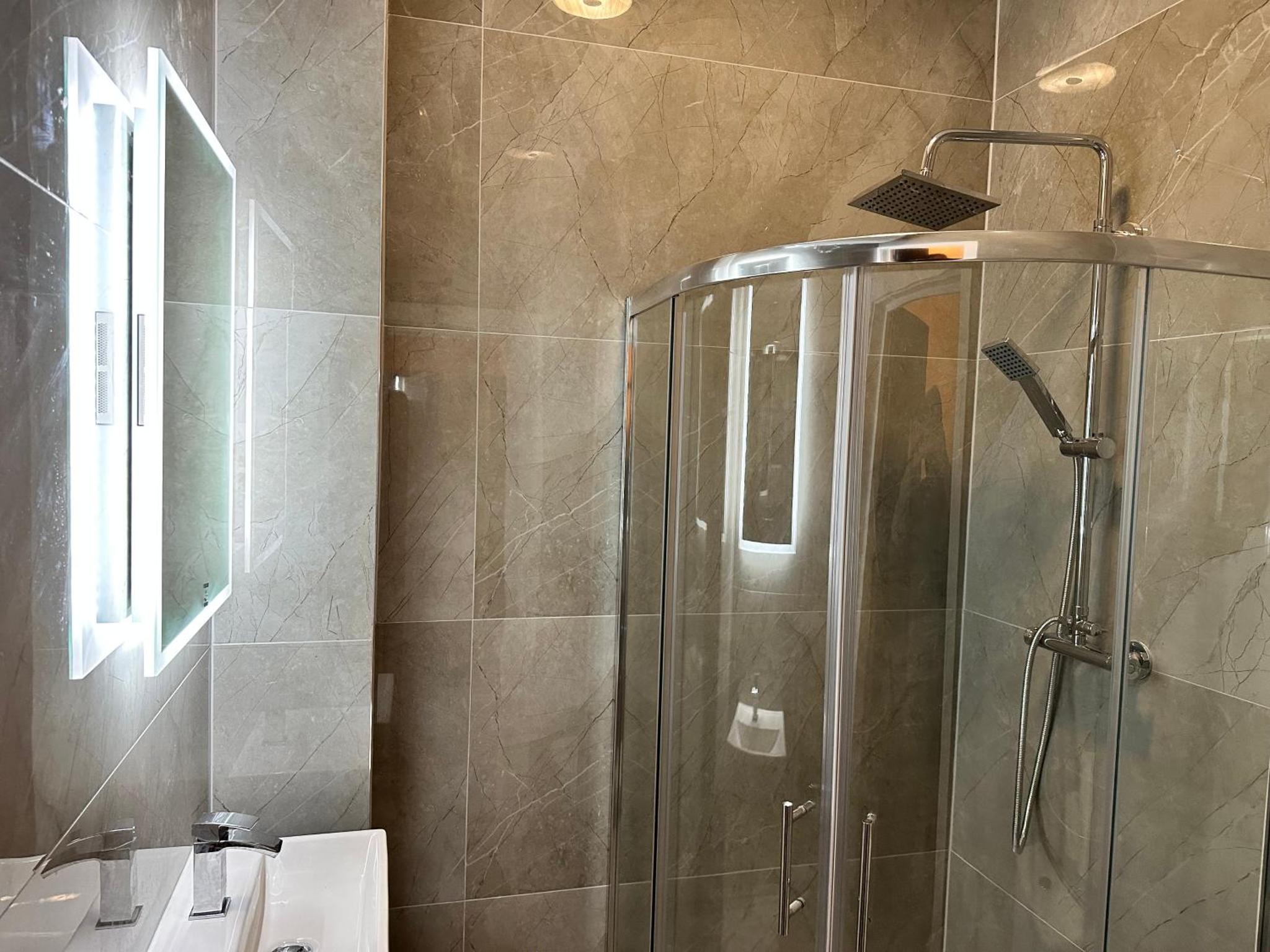 a shower in a bathroom with a glass shower stall at Green Ariana Hotel - near Wembley and central London in London