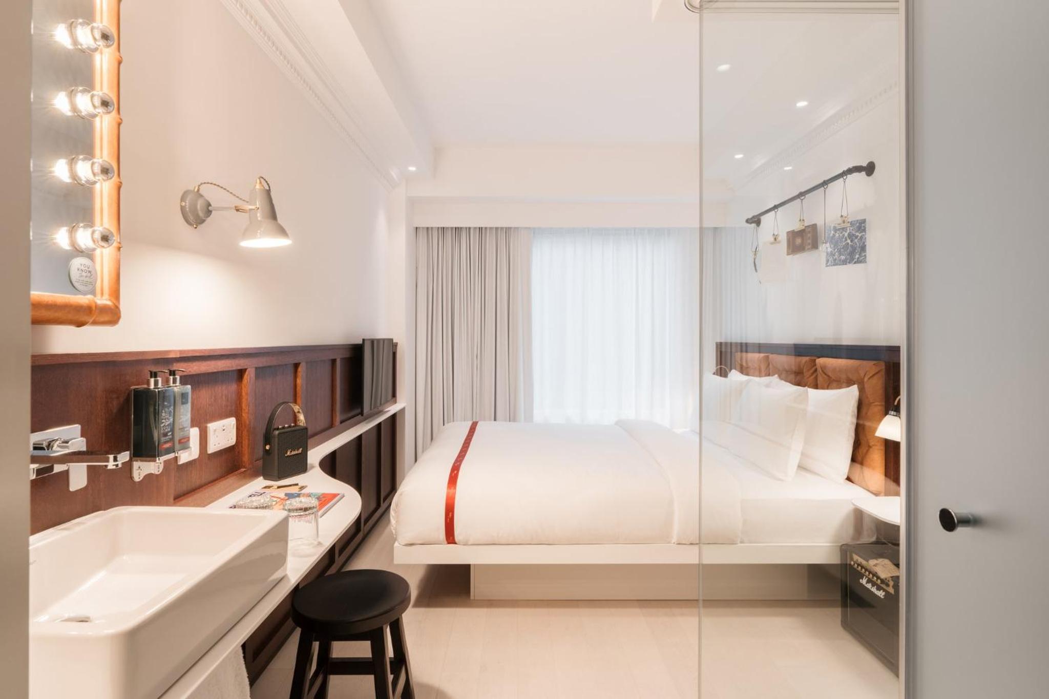 a bedroom with a bed and a sink and a tub at Ruby Stella Hotel London in London