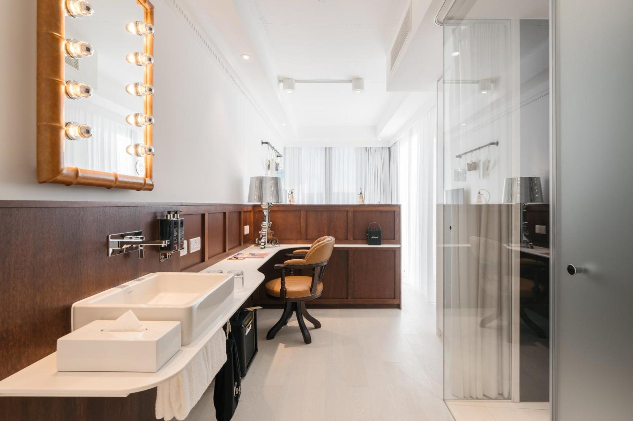 a bathroom with a sink and a desk with a chair at Ruby Stella Hotel London in London +39 photos