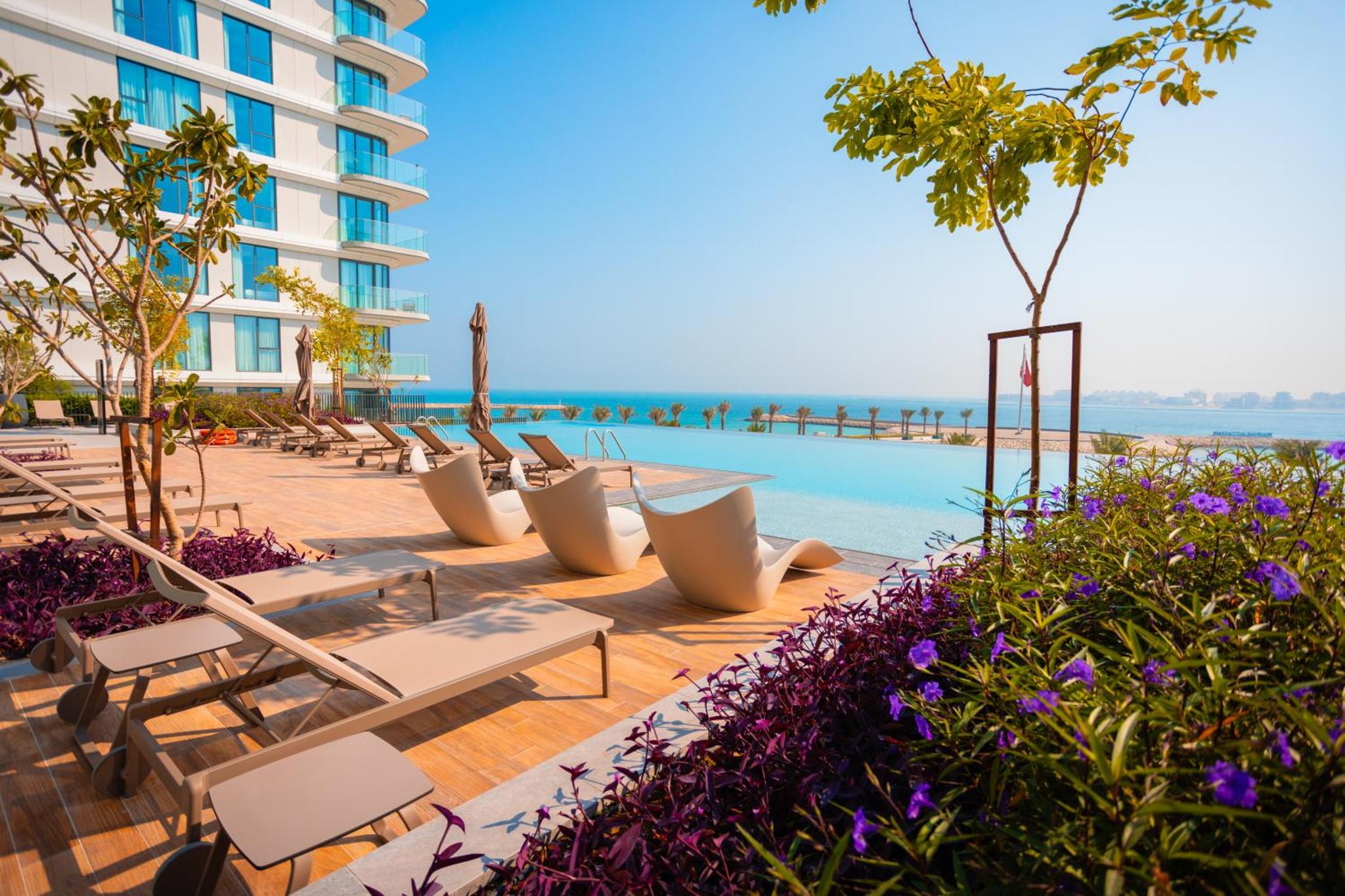 a row of tables and chairs next to a pool at Spacious 2BDR Address Vista PrivateTerrace in Amwaj Island