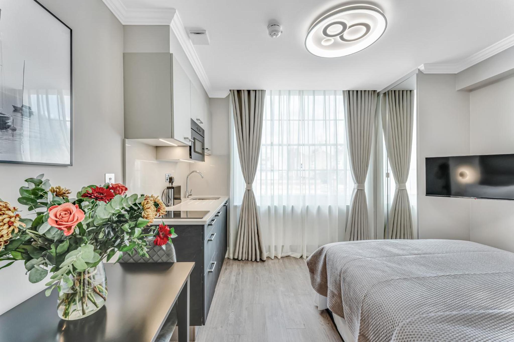 a bedroom with a bed and a table with a vase of flowers at Cleveland Residences Bloomsbury in London