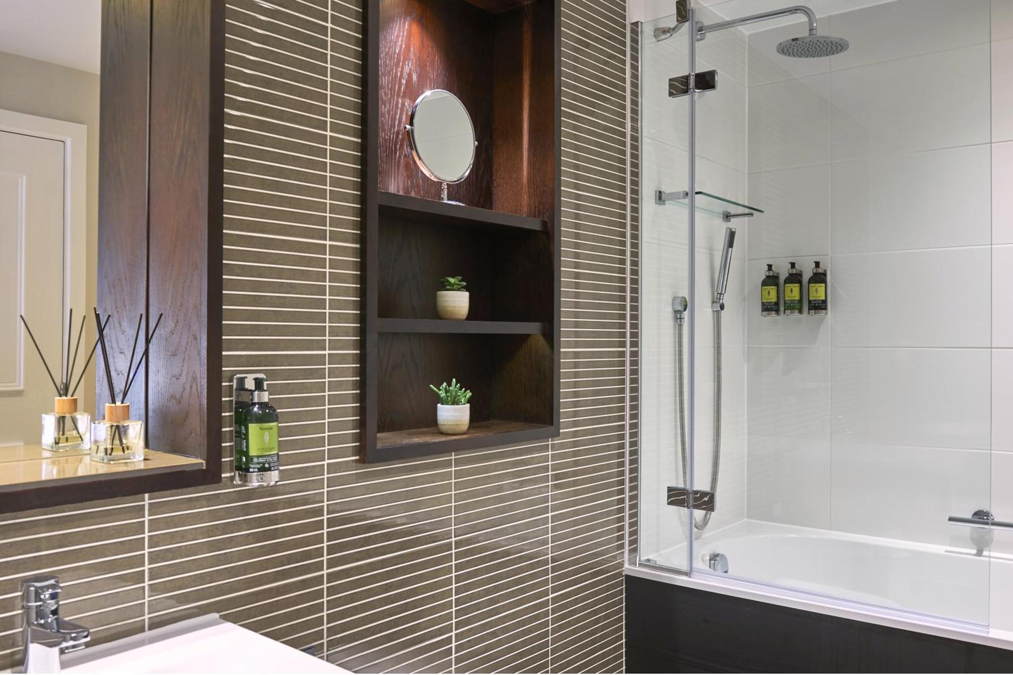 a bathroom with a shower and a sink and a tub at Fraser Suites Queens Gate in London