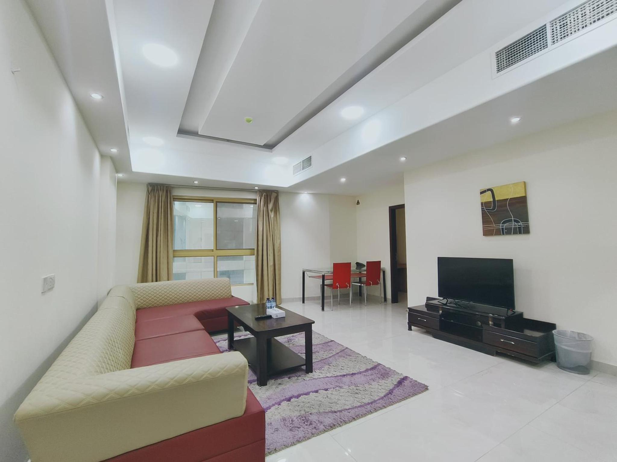 a living room with a couch and a flat screen tv at Marina Tower in Juffair