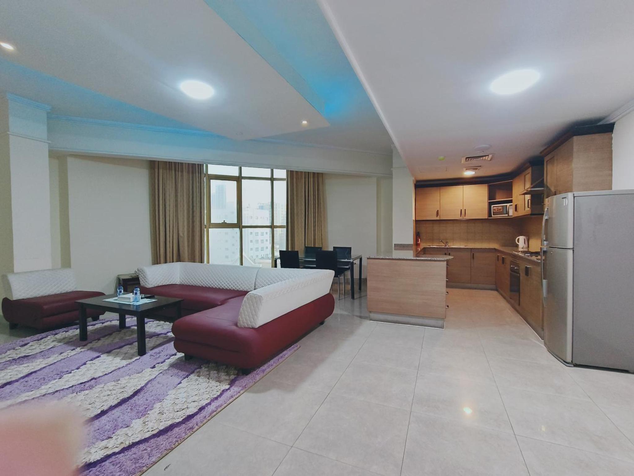 a living room with a couch and a kitchen at Marina Tower in Juffair