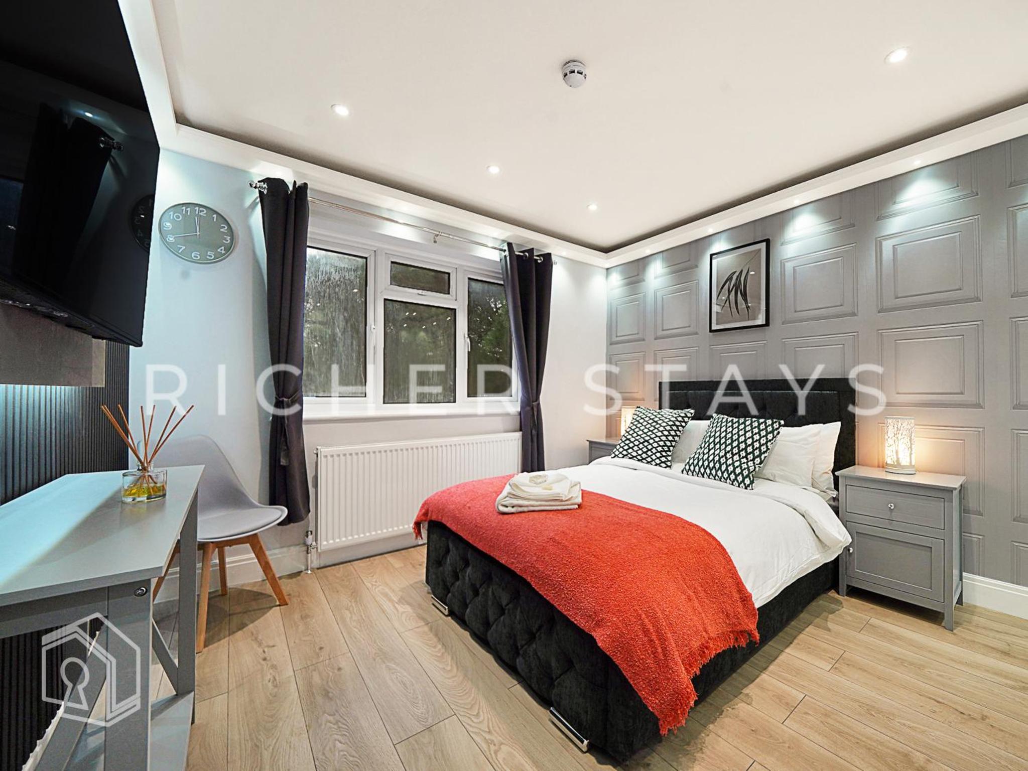 a bedroom with a bed and a desk and a television at Leyton Guest Rooms - Rooms and Amenities in London