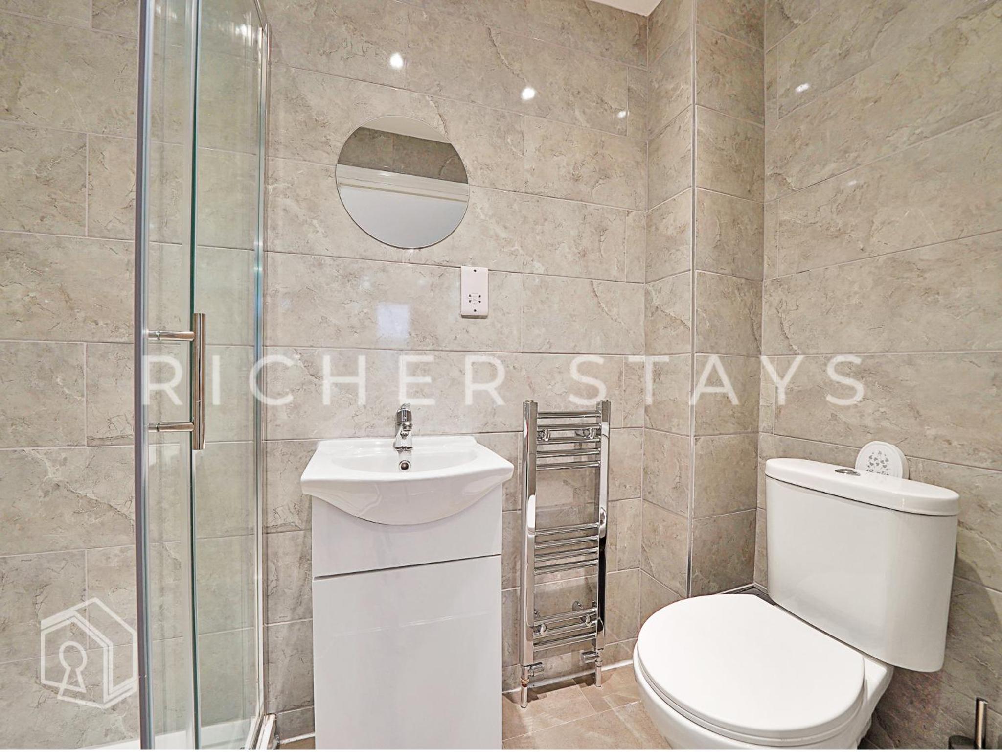 a bathroom with a toilet and a glass shower at Leyton Guest Rooms - Rooms and Amenities in London +12 photos
