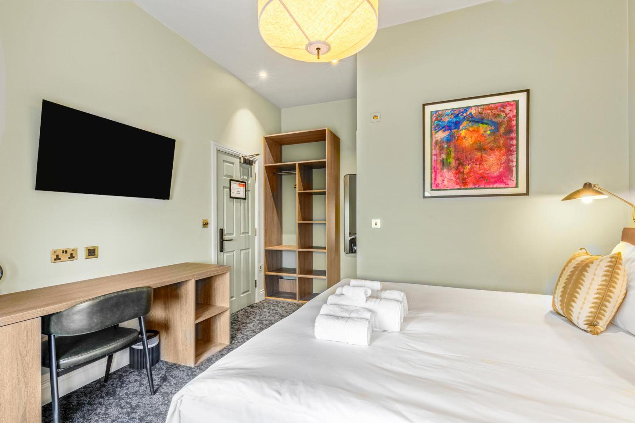 a bedroom with a bed and a desk and a television at Clapham Guest House in London