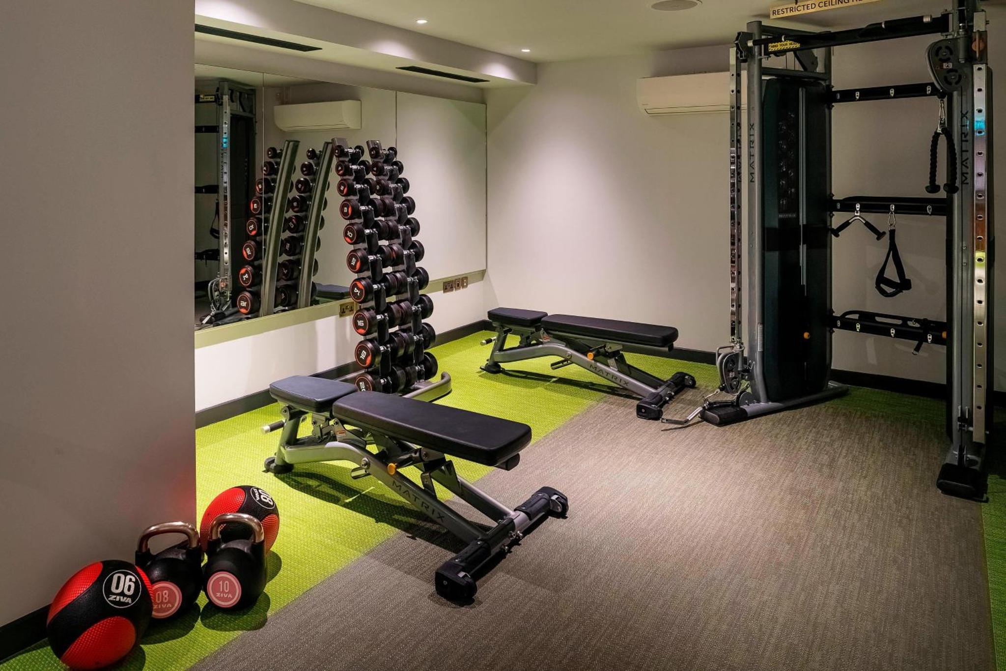 a gym with a row of tread machines and weights at The Dixon, Tower Bridge, Autograph Collection in London