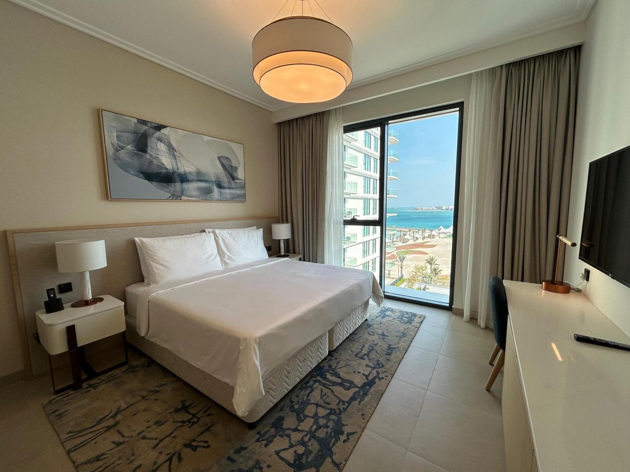a hotel room with a bed and a large window at Address Residence Marassi Vista Bahrain in Muharraq