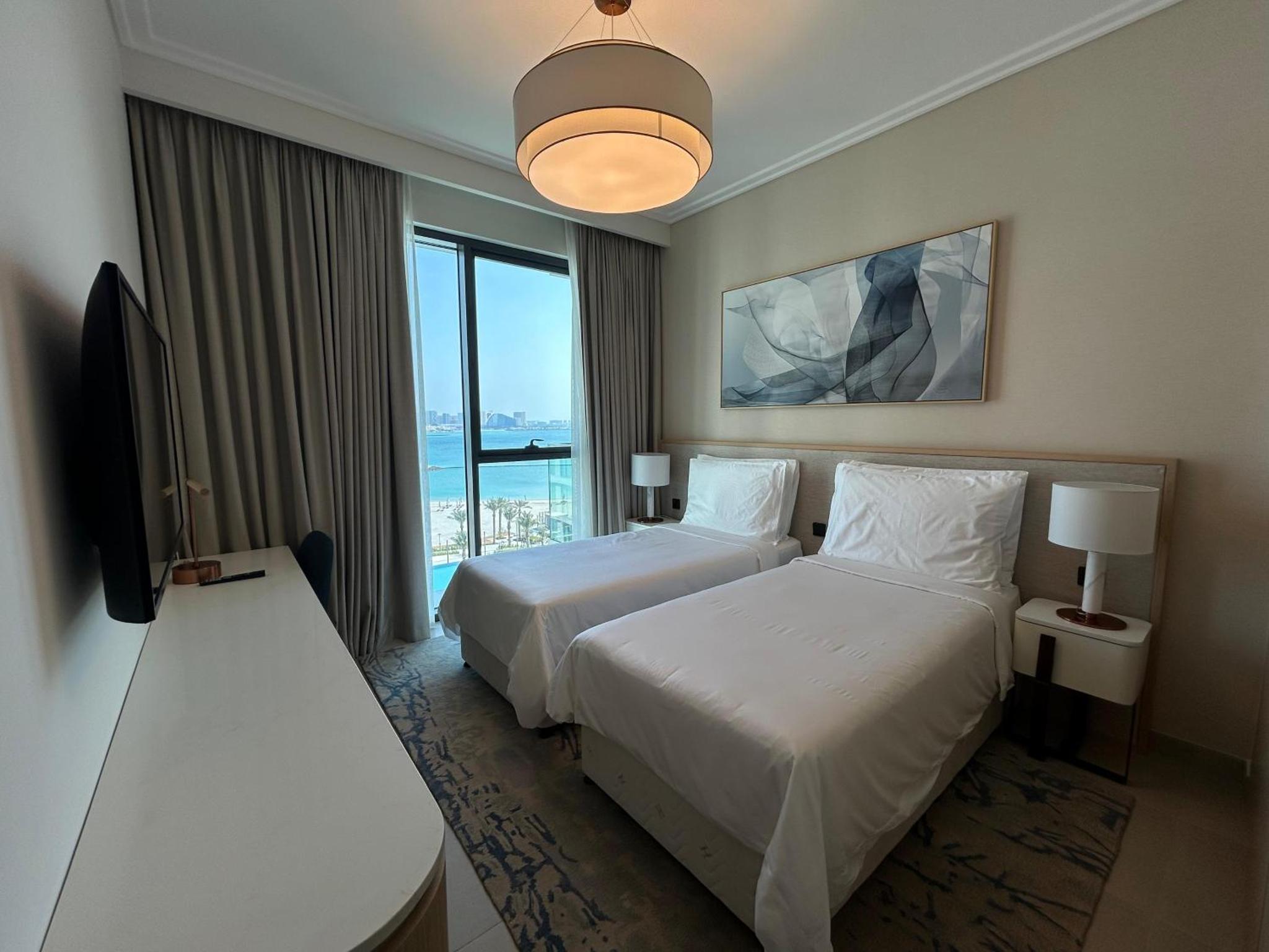 a hotel room with two beds and a flat screen tv at Address Residence Marassi Vista Bahrain in Muharraq +61 photos