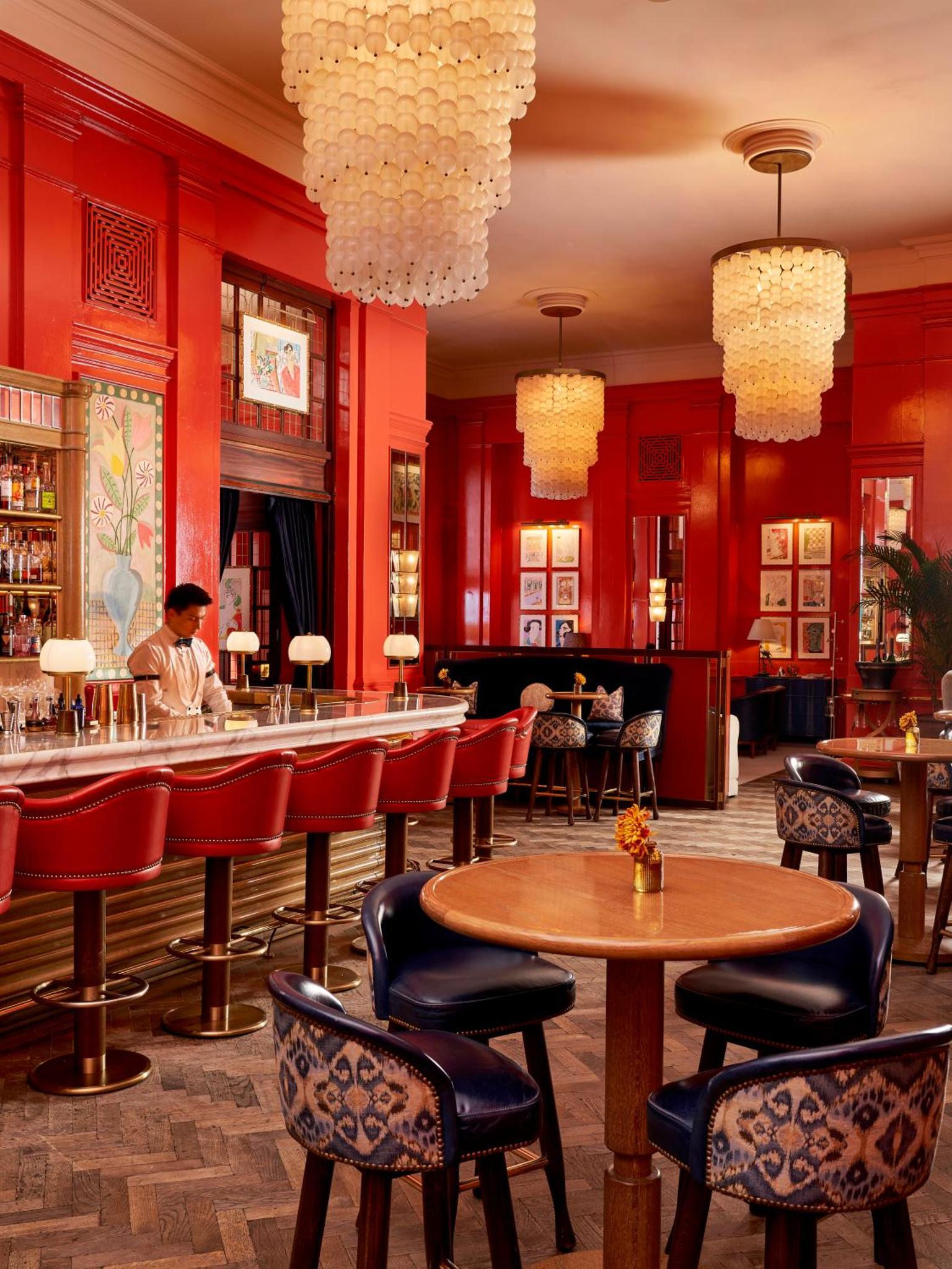 a restaurant with red walls and a bar with tables and chairs at The Bloomsbury Hotel in London