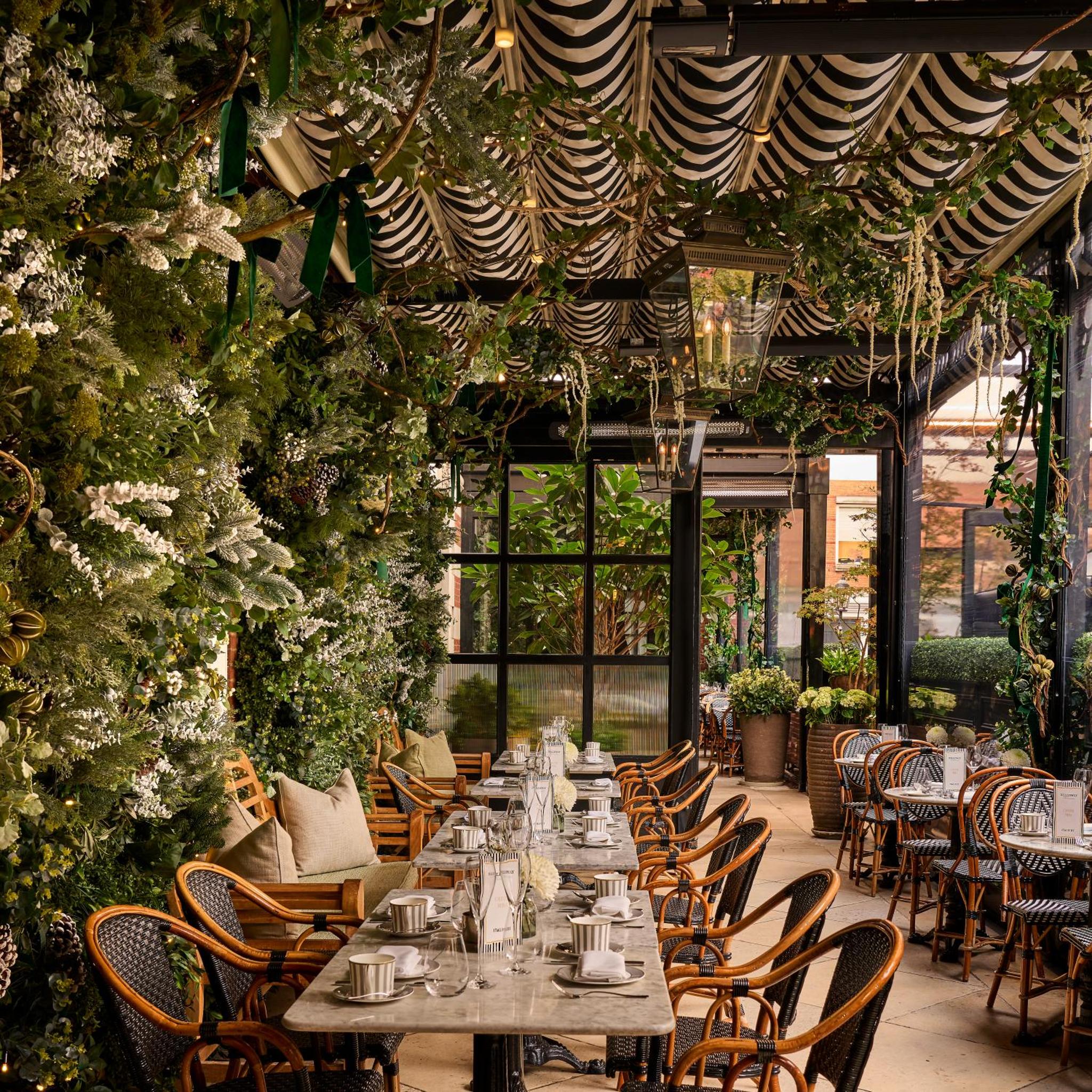 a dining room with tables and chairs and plants at The Bloomsbury Hotel in London