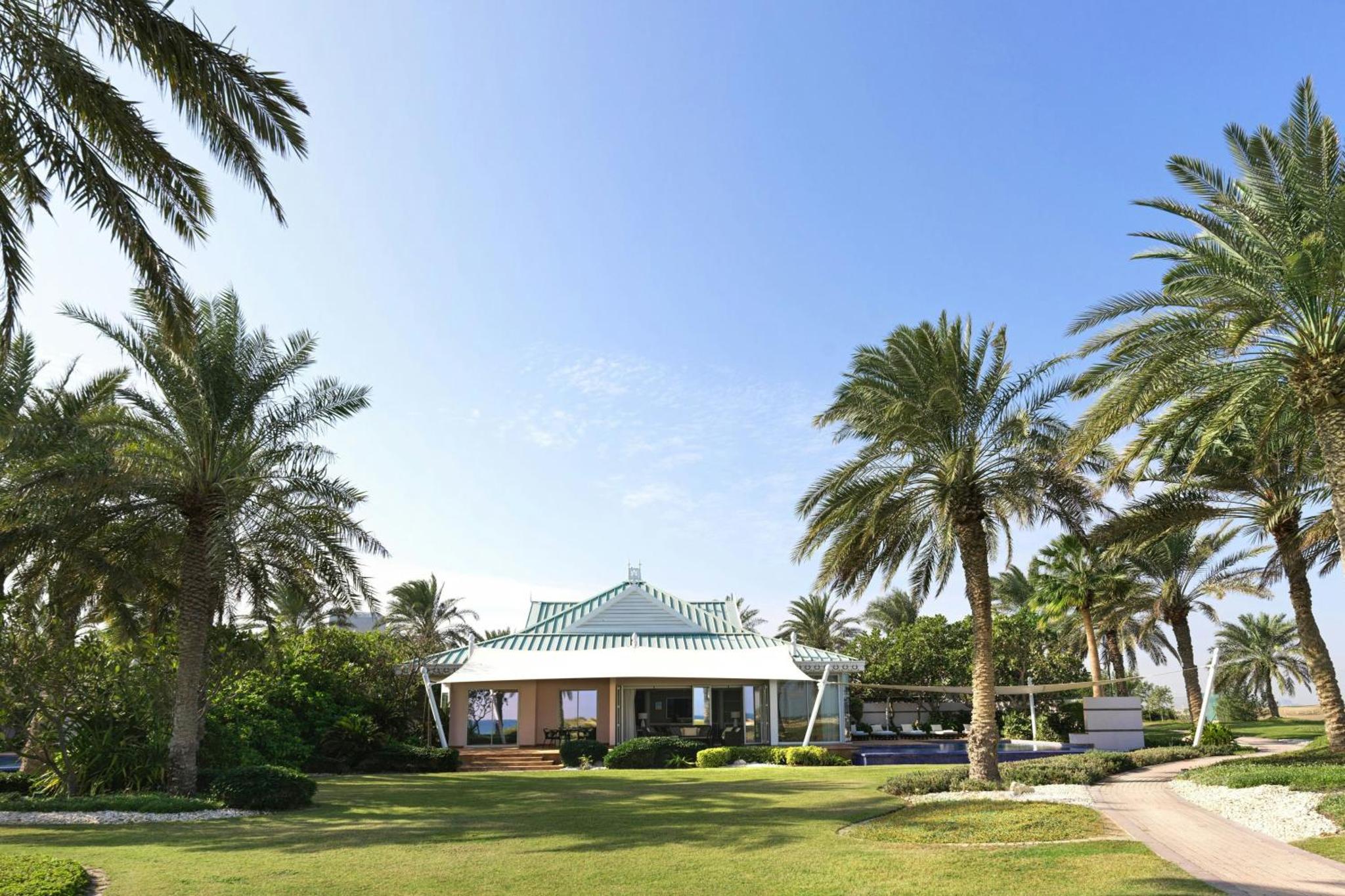 a house with palm trees in front of it at The Ritz-Carlton, Bahrain in Manama