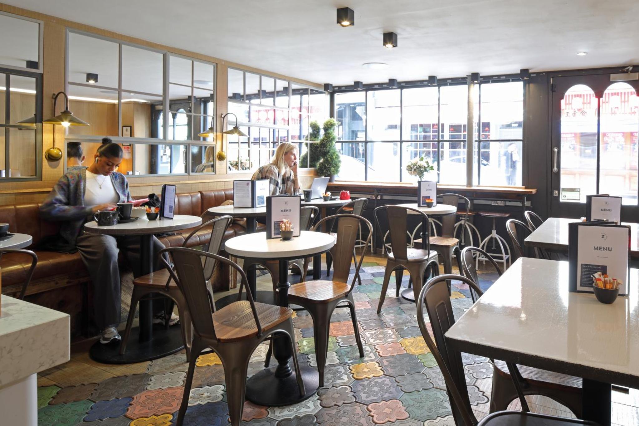 two people sitting in a restaurant with tables and chairs at The Z Hotel Soho in London +22 photos