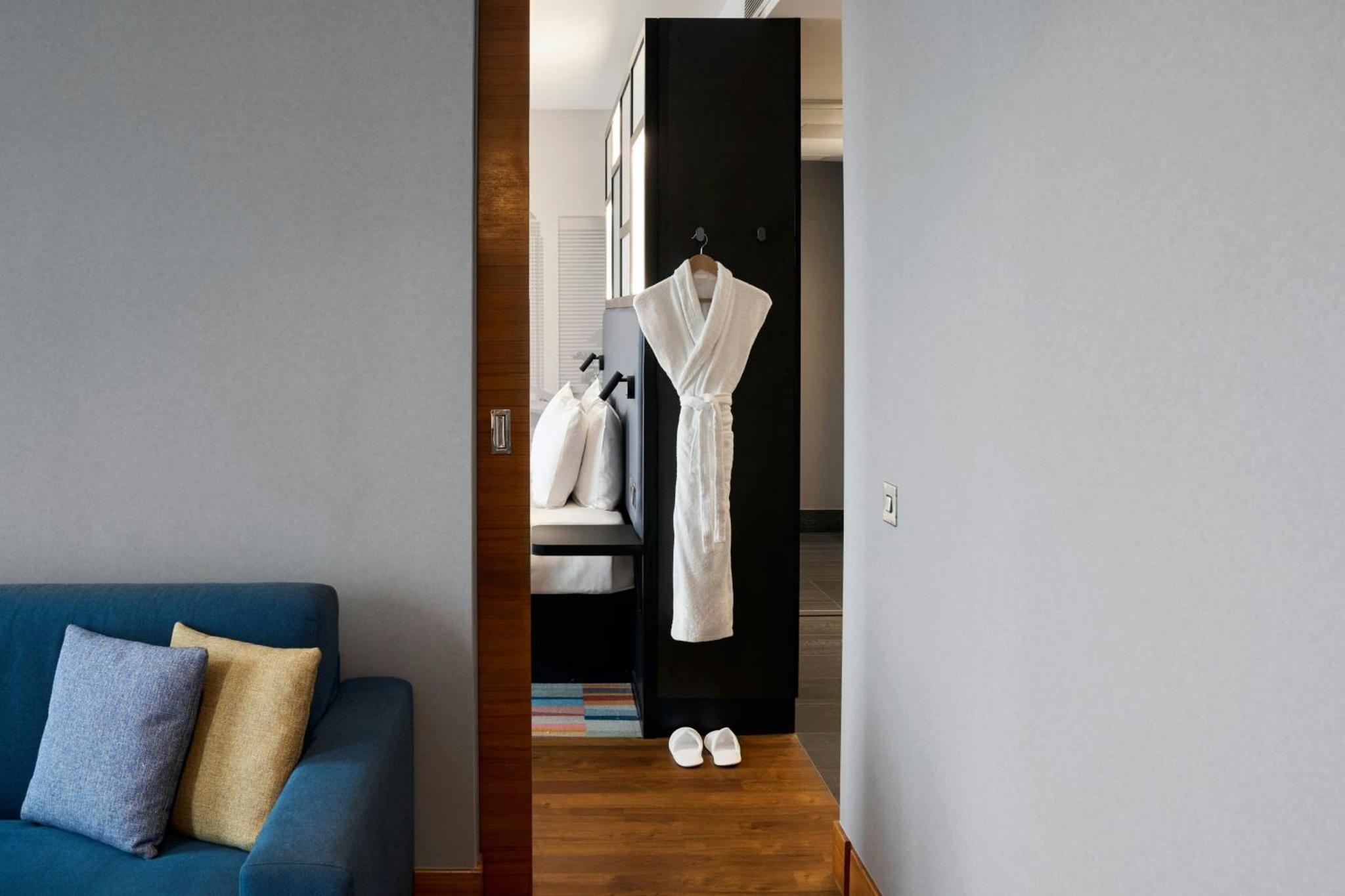 a living room with a blue couch and a mirror at Aloft London Excel in London