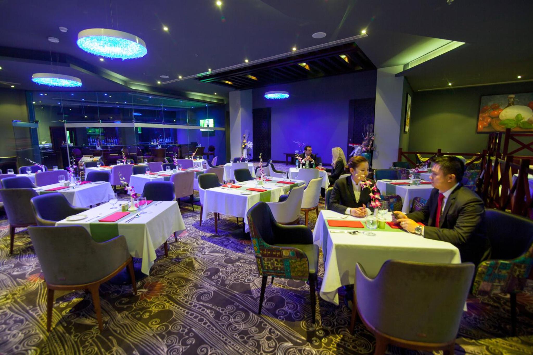 a group of people sitting at tables in a restaurant at Premier Hotel in Manama +36 photos