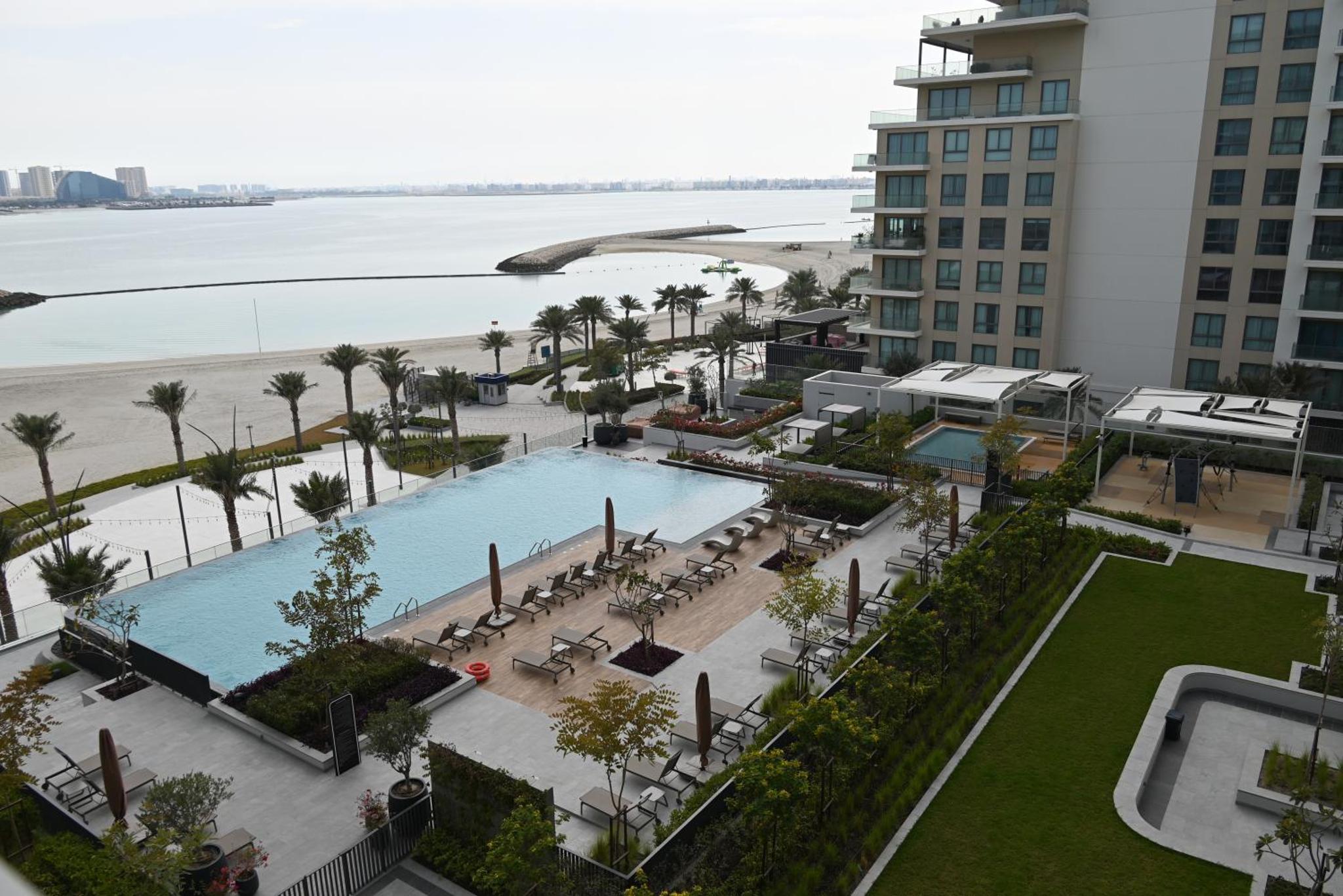 an aerial view of a resort with a pool and the beach at Address Vista Bahrain in Rayyā