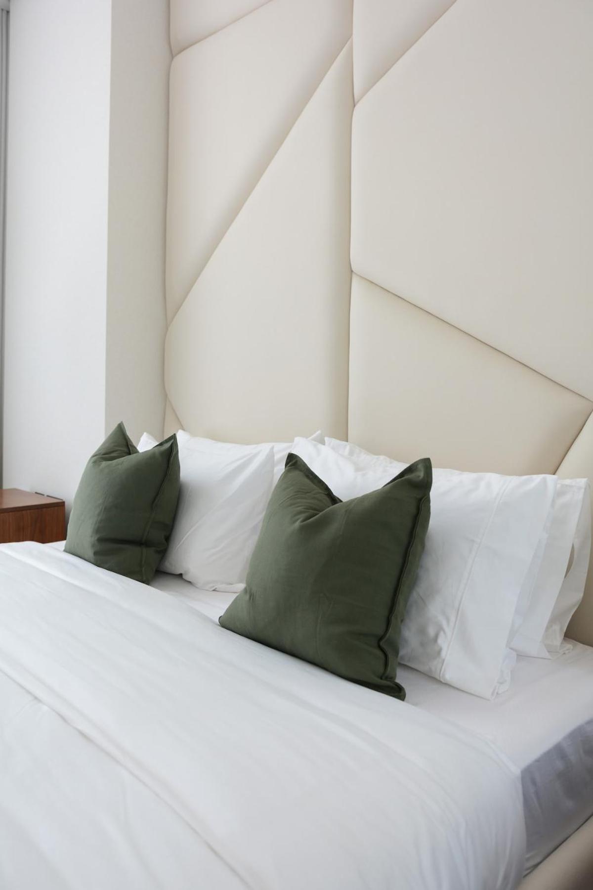 a white bed with green and white pillows at TOP Luxurious and Cozy 2BR with 5 mins to Bahrain Bay in Manama +41 photos