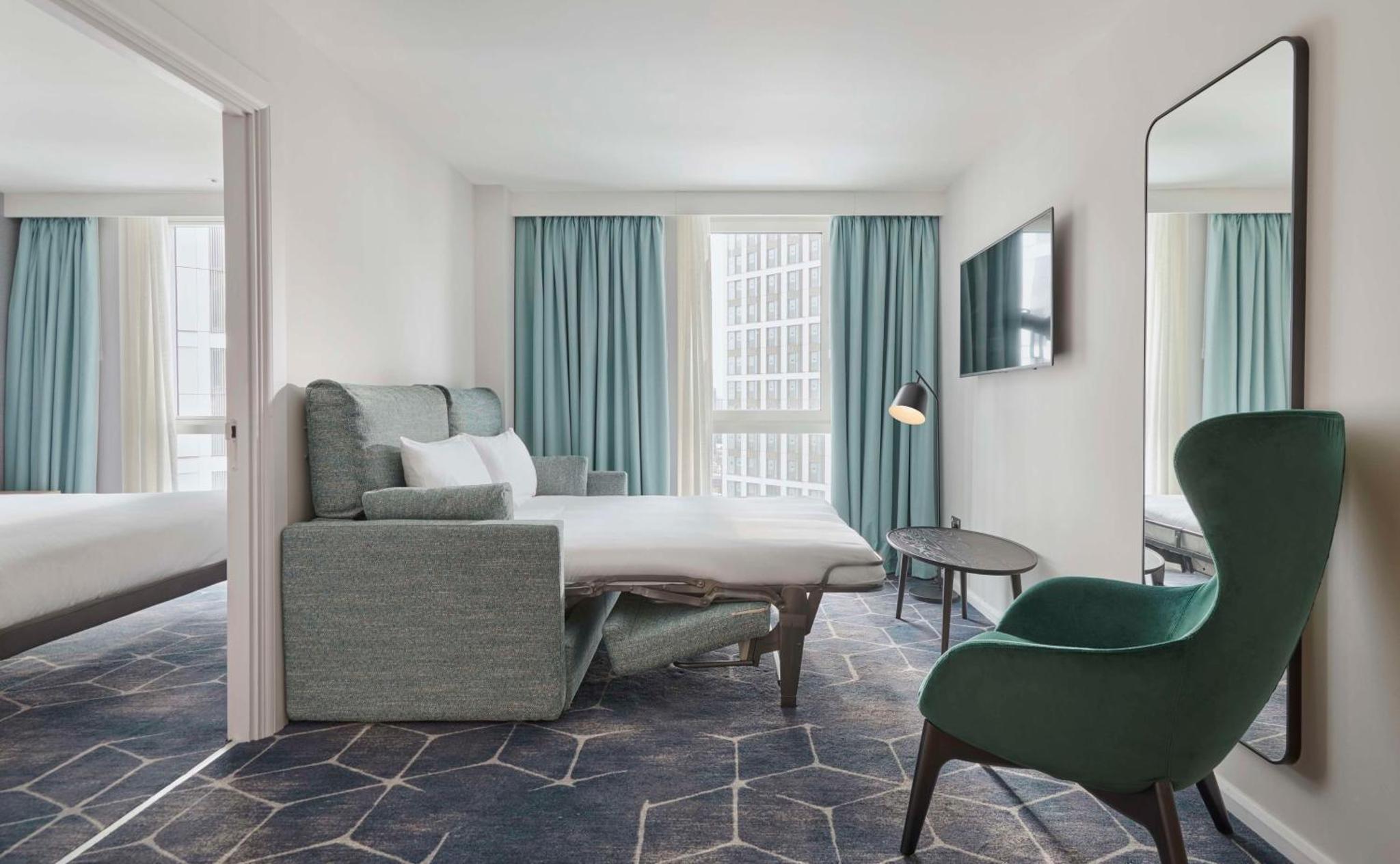 a hotel room with a bed and a desk and a chair at Hyatt House London Stratford - Aparthotel in London