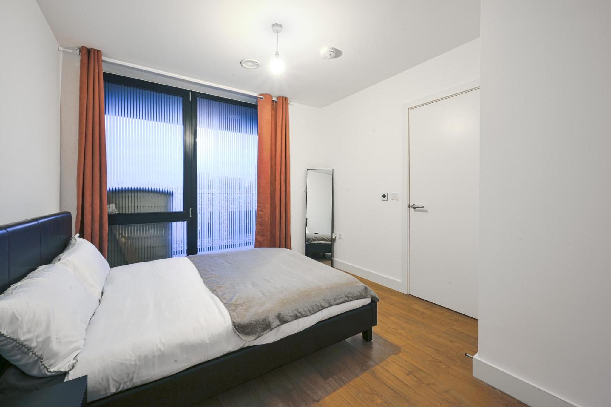 a bedroom with a bed and a large window at CANARY WHARF E14 MODERN 1 Bed APARTMENT HIGH SPEC in London