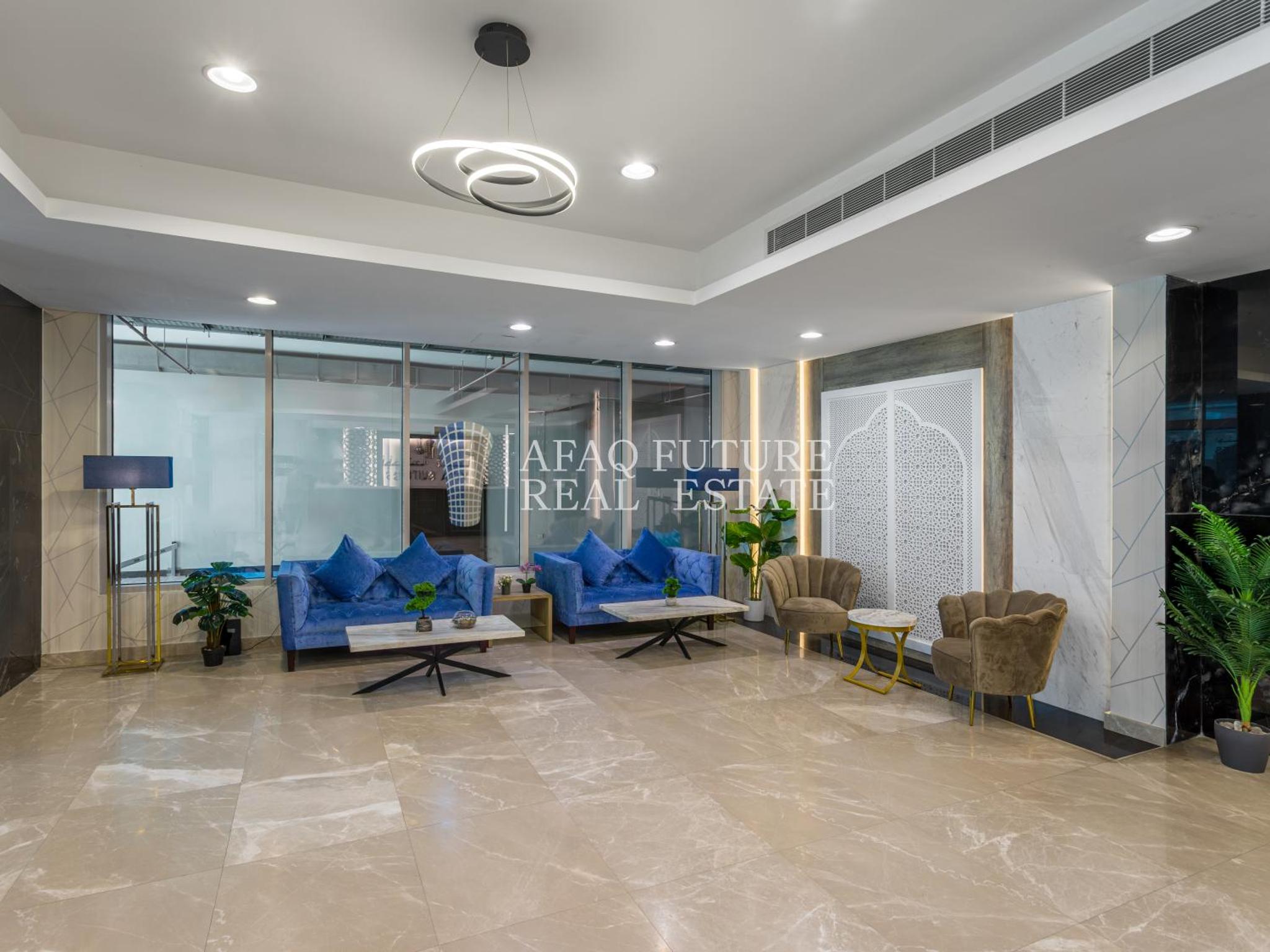 a lobby with blue couches and chairs in a building at Vita Suites in Manama