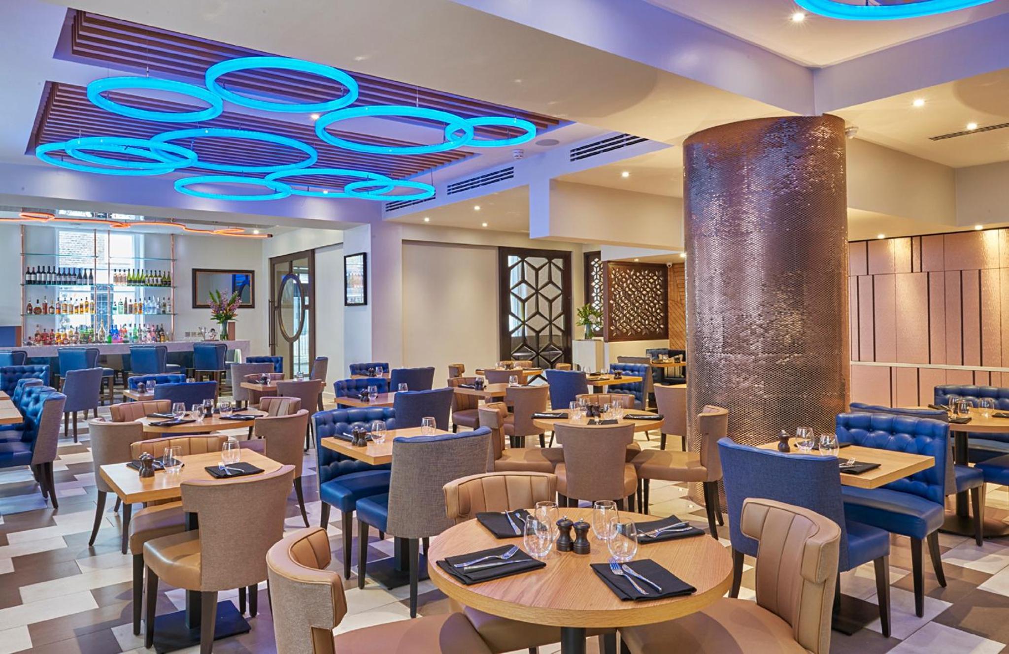 a restaurant with tables and chairs and a blue ceiling at Norfolk Towers Paddington in London