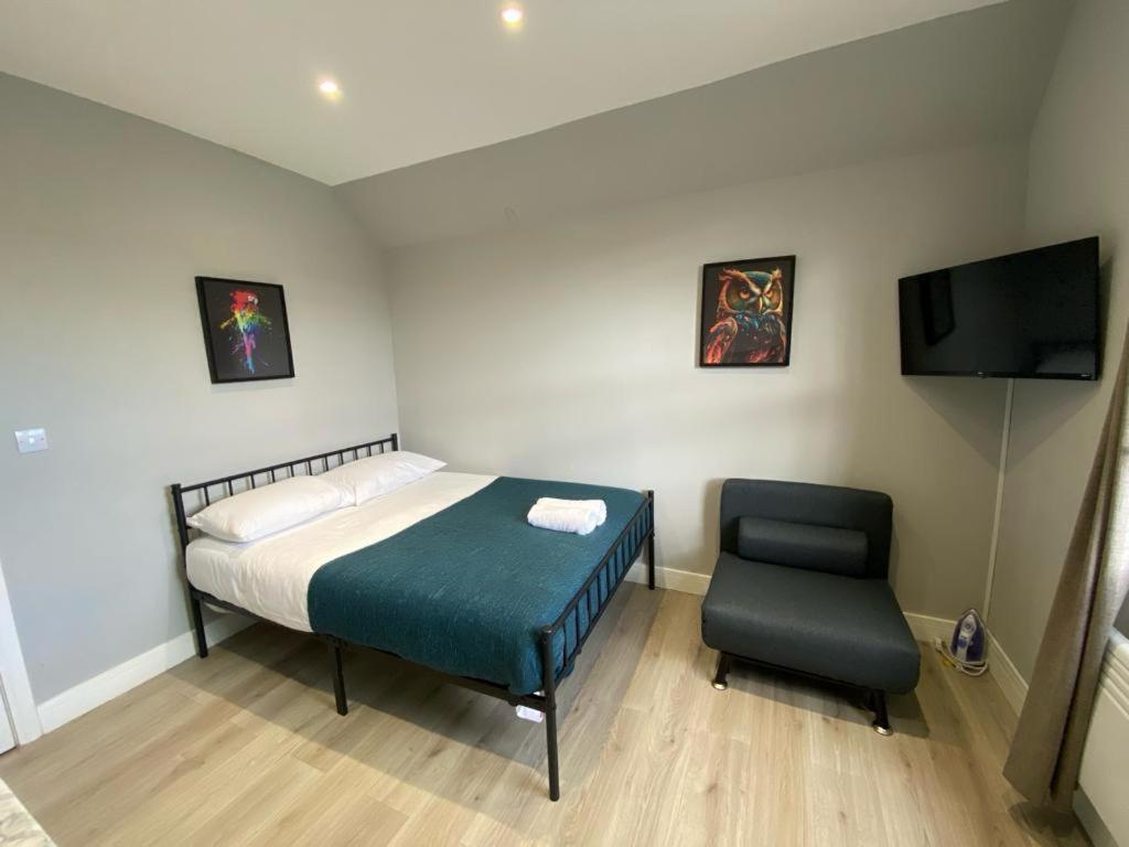 a small bedroom with a bed and a chair at London Central Suits - Comfortable Rooms in London