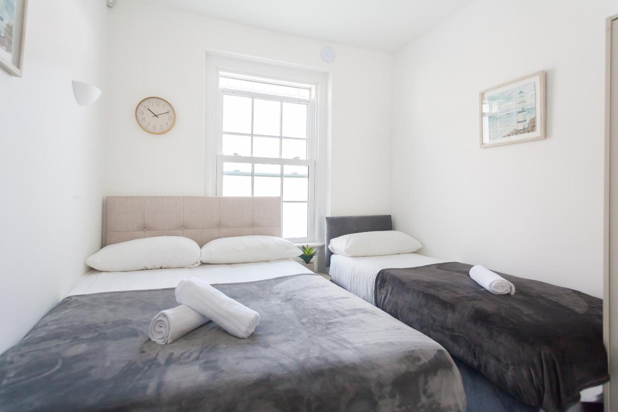 a bedroom with two beds and a clock on the wall at London Central Suits - Comfortable Rooms in London