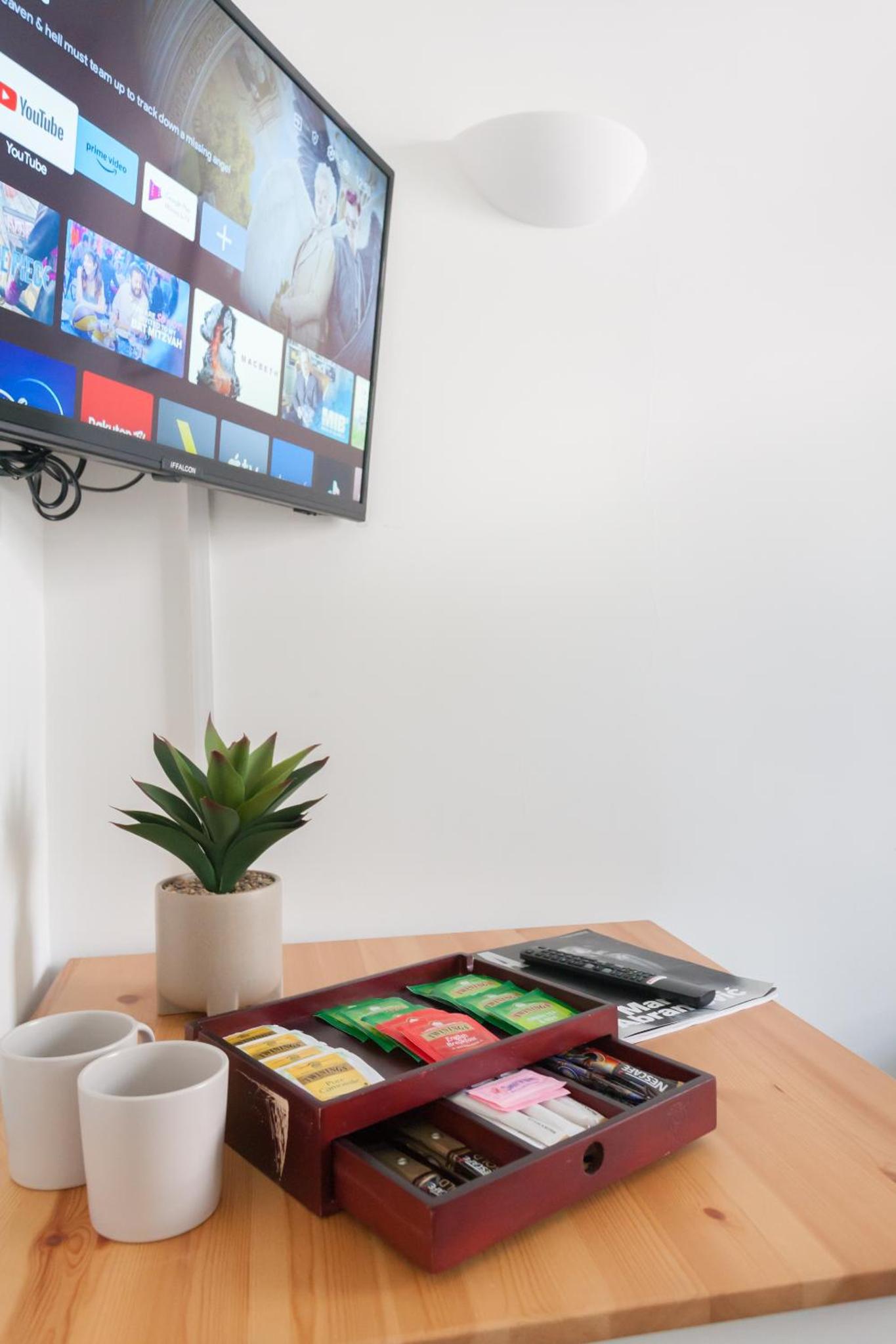 a wooden table with a tv on a wall at London Central Suits - Comfortable Rooms in London