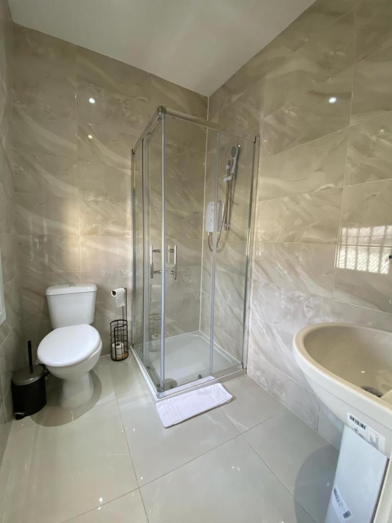 a bathroom with a shower and a toilet and a sink at London Central Suits - Comfortable Rooms in London