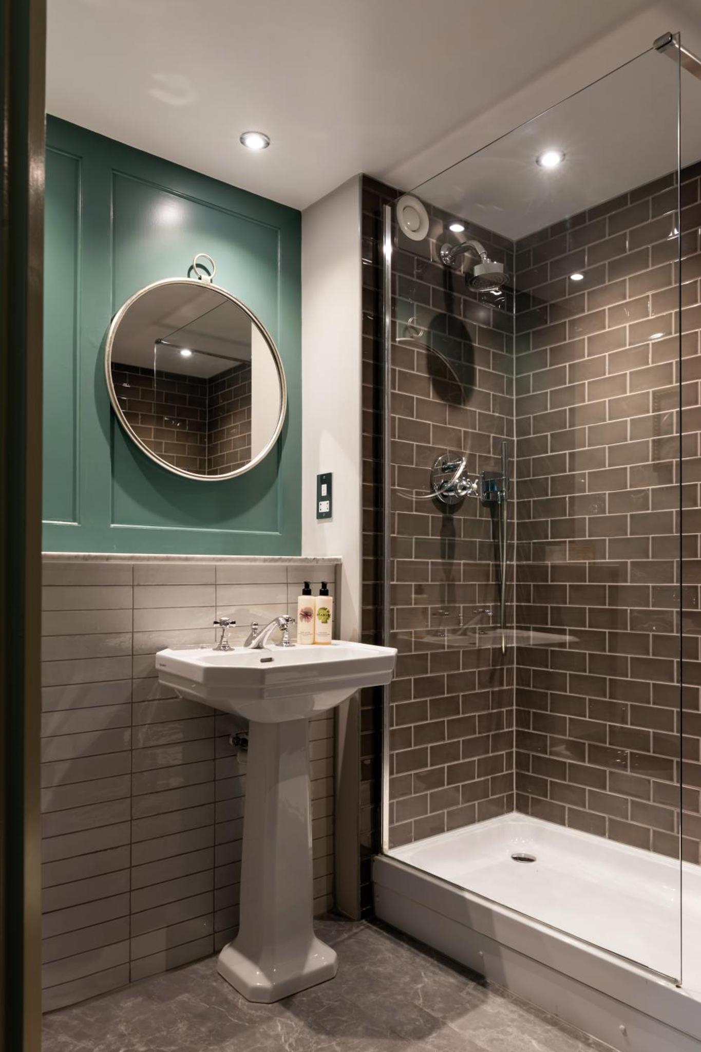 a bathroom with a sink and a shower and a mirror at Coach & Horses Hotel in London +54 photos