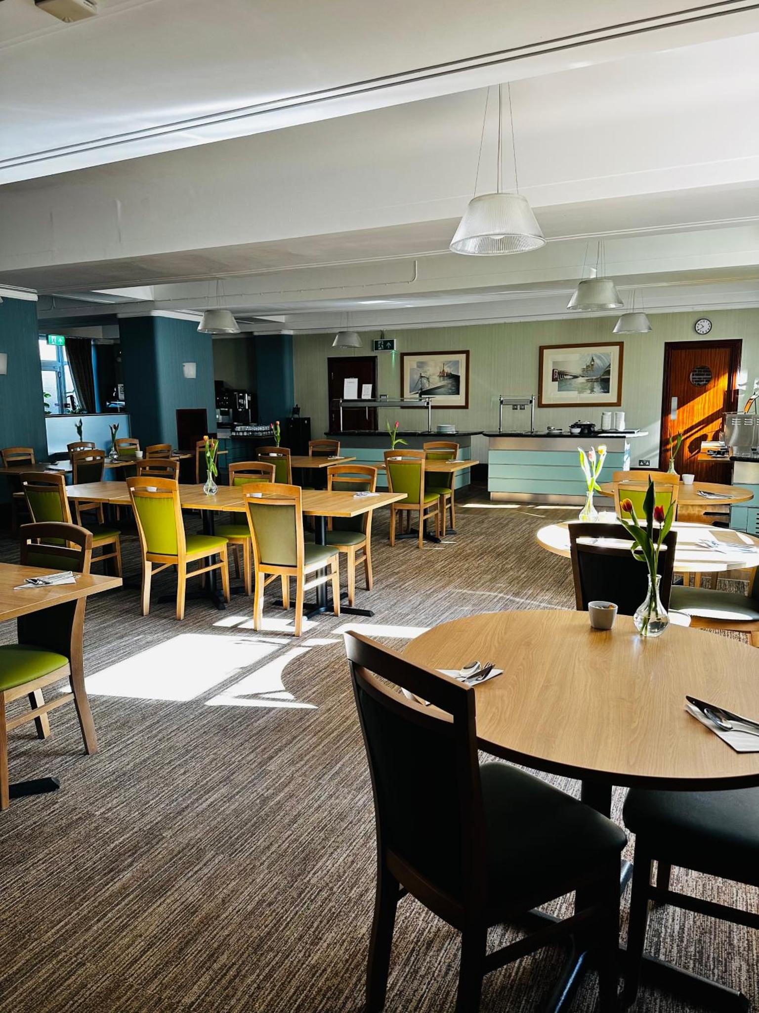 a dining room with tables and chairs and a cafeteria at Vincent House London Residence in London