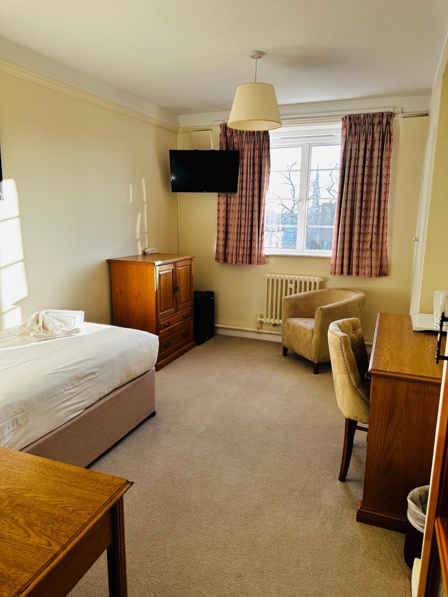 a hotel room with a bed and a chair and a desk at Vincent House London Residence in London