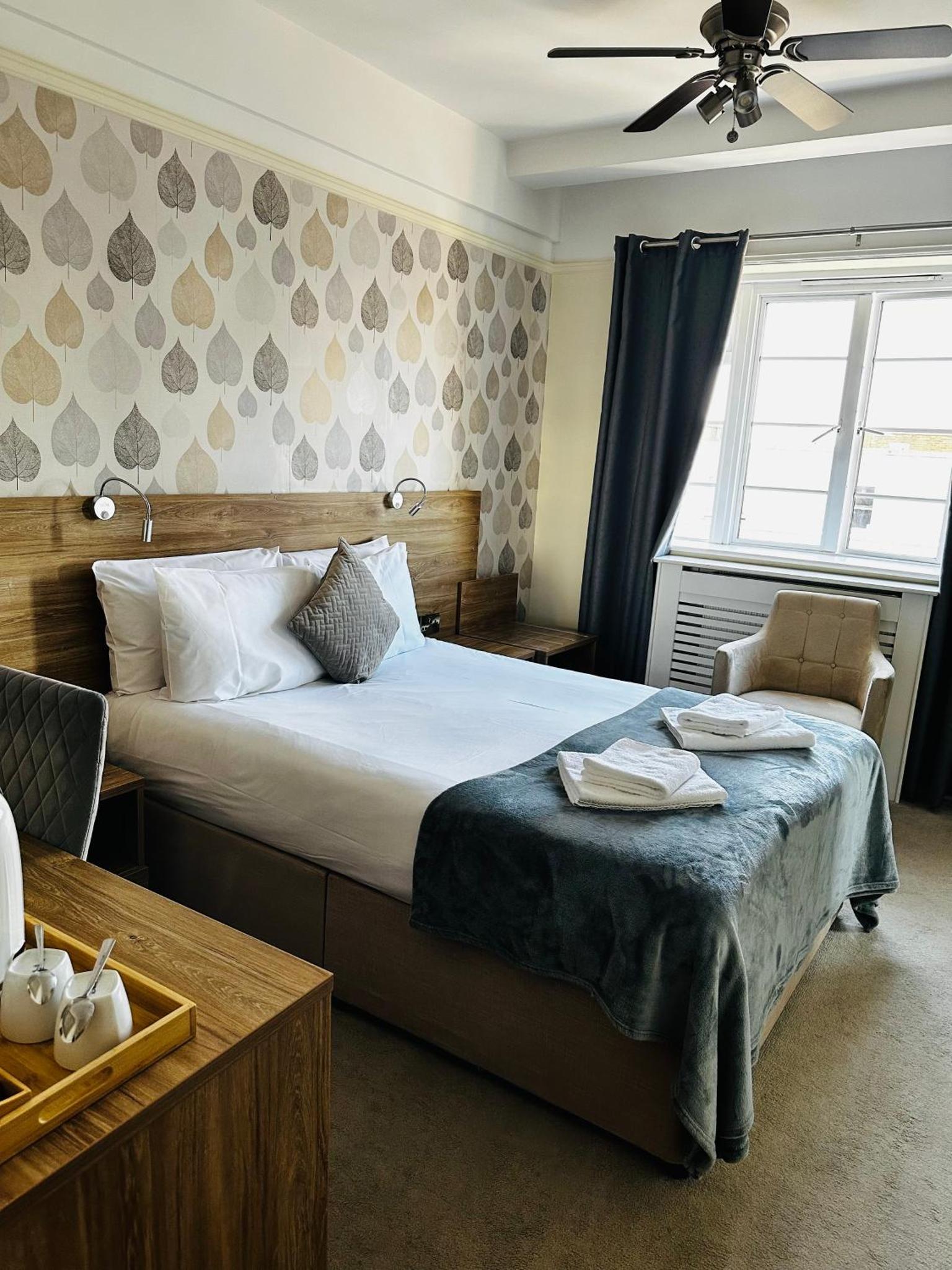 a bedroom with a bed and a chair and a window at Vincent House London Residence in London