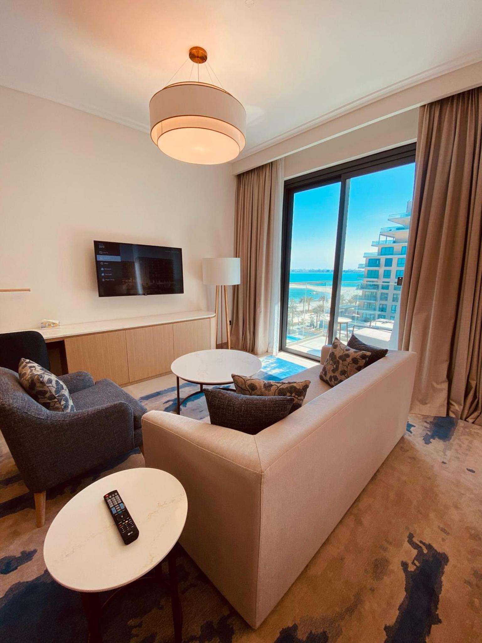 a living room with a couch and a large window at Address Vista Bahrain in Rayyā