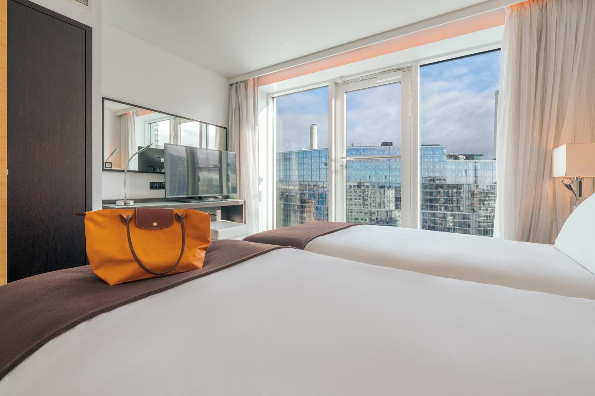 a bedroom with a large bed with a large window at Pestana Chelsea Bridge Hotel & SPA in London